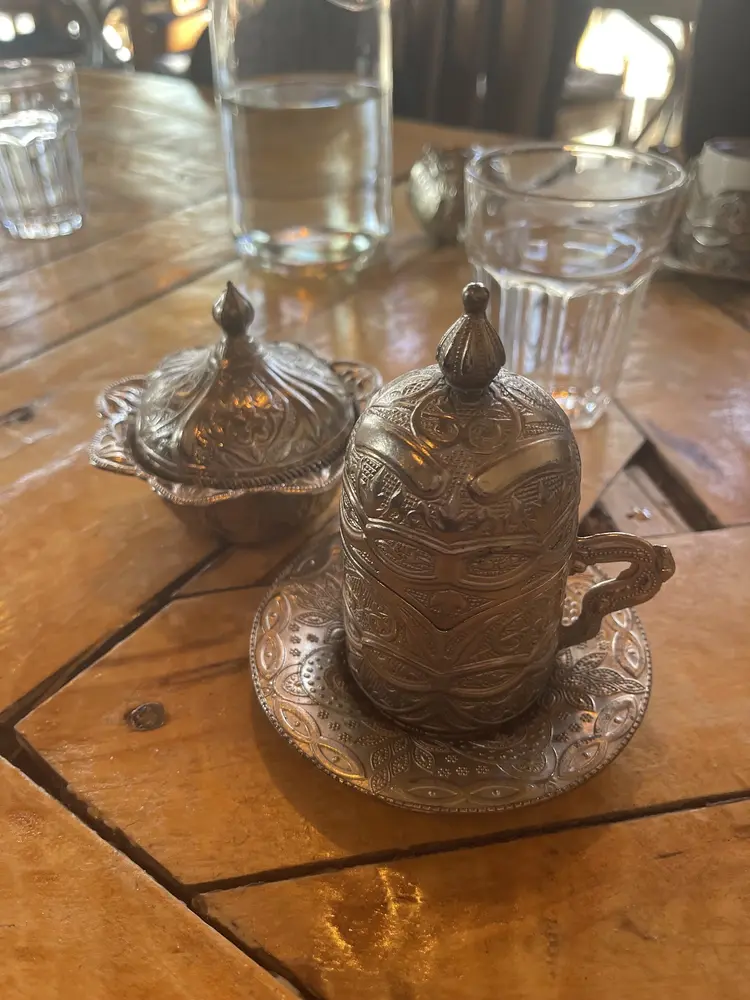 Turkish coffee served in an ornate engraved copper cup with lokum bowl